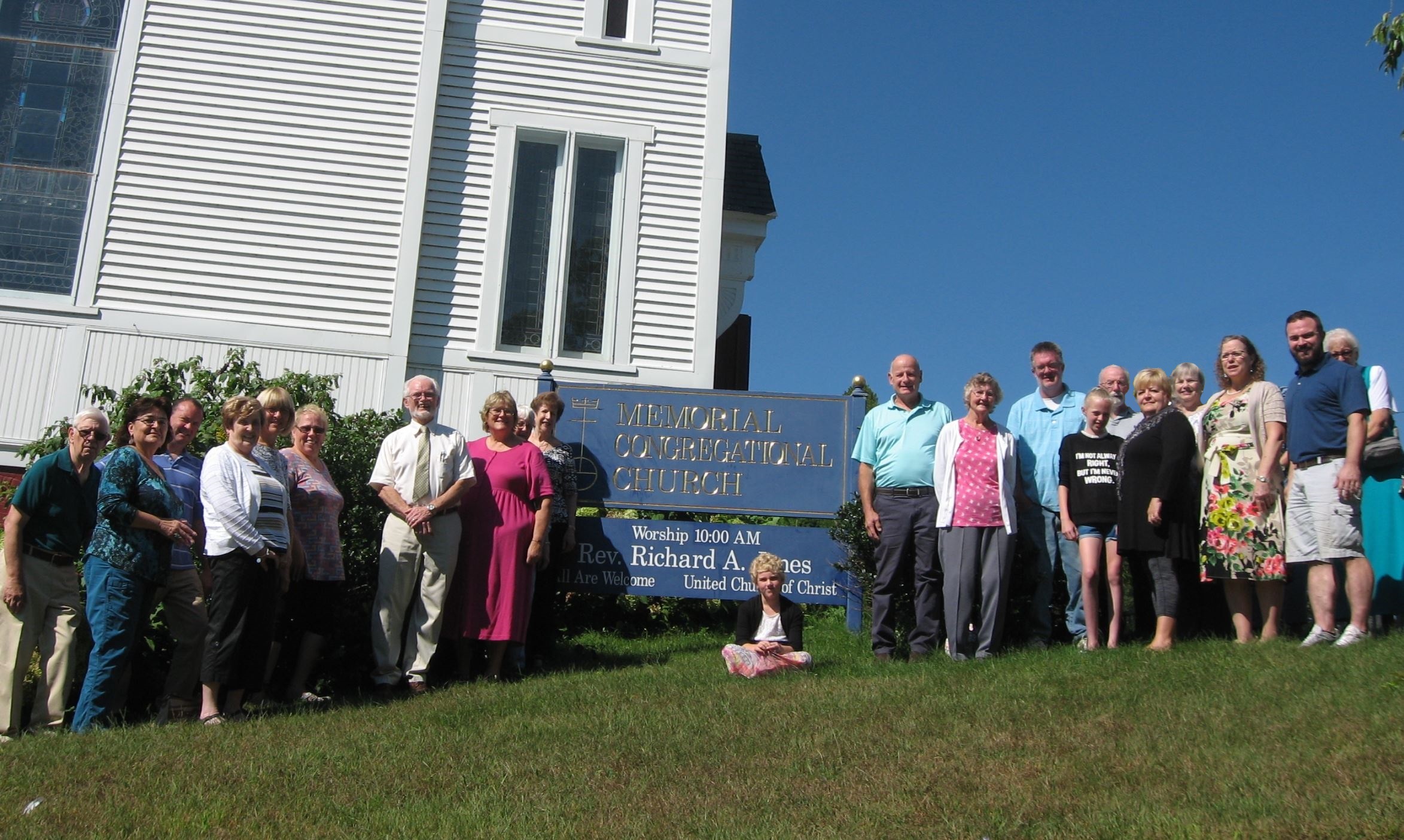 Members of the congregation stand in front of the church building